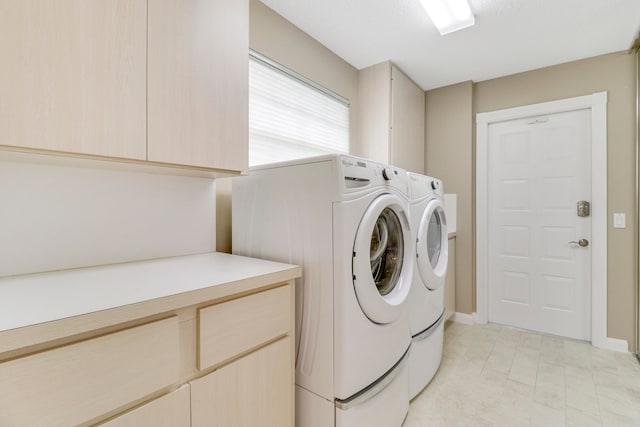 washroom featuring cabinets, light tile patterned floors, and washer and clothes dryer