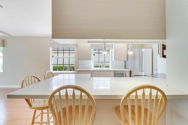 interior space with sink, stainless steel appliances, kitchen peninsula, and light hardwood / wood-style floors