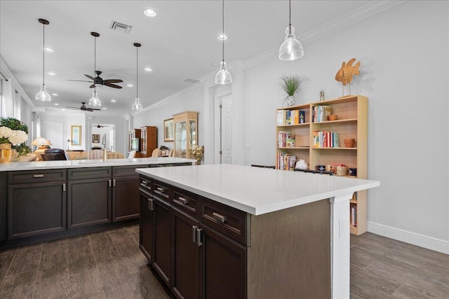 kitchen with dark brown cabinetry, ceiling fan, dark wood-type flooring, and ornamental molding