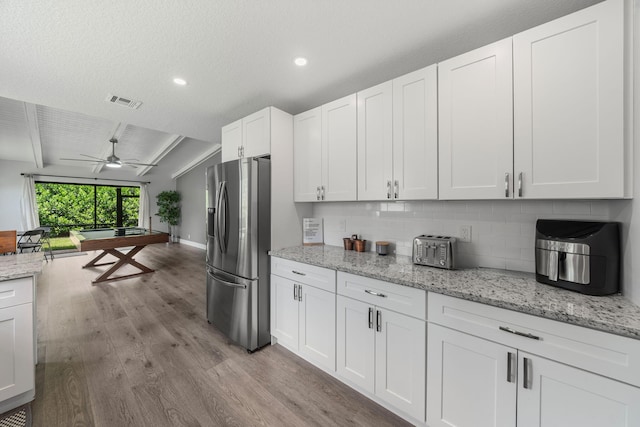 kitchen featuring decorative backsplash, light wood-type flooring, ceiling fan, beam ceiling, and stainless steel fridge