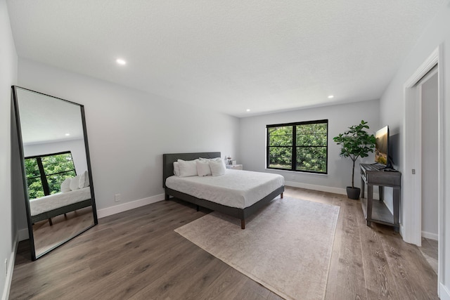 bedroom with a textured ceiling, multiple windows, and hardwood / wood-style floors