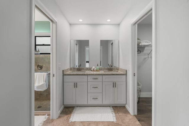 bathroom with double sink vanity, tiled shower, and tile patterned floors