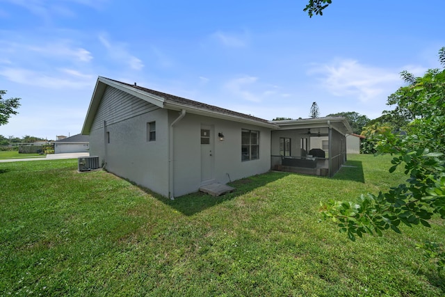 rear view of house featuring cooling unit and a lawn