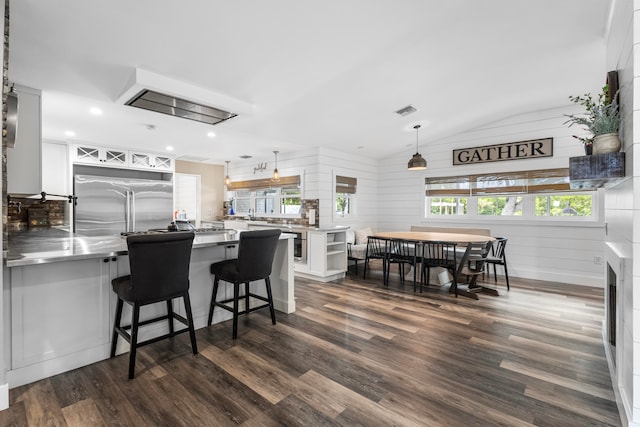 kitchen featuring stainless steel counters, dark wood-type flooring, built in refrigerator, white cabinetry, and hanging light fixtures