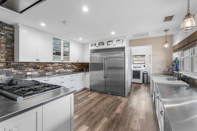 kitchen featuring stainless steel appliances, decorative backsplash, stainless steel counters, white cabinets, and dark hardwood / wood-style flooring