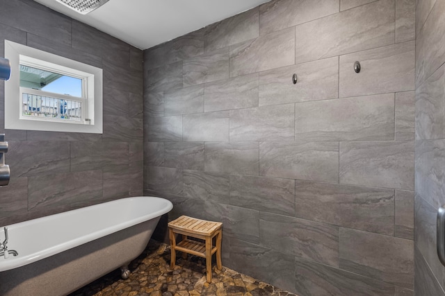 bathroom with a bathtub, tile patterned floors, and tile walls