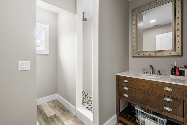 bathroom featuring hardwood / wood-style flooring, vanity, and walk in shower