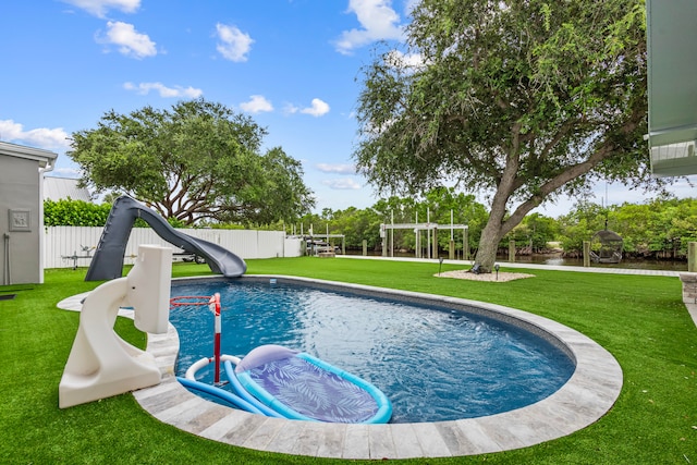 view of swimming pool with a water slide and a lawn