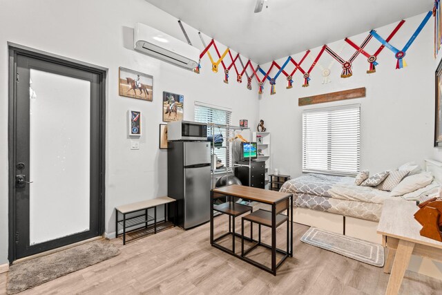 living room featuring light wood-type flooring, a wall mounted AC, and a healthy amount of sunlight