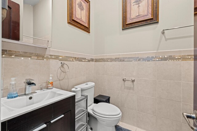 bathroom with vanity, toilet, and tile walls