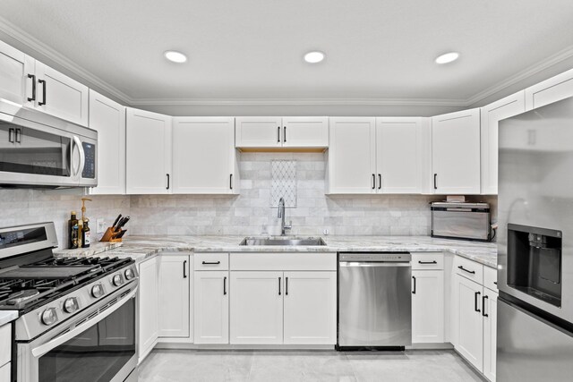 kitchen featuring light stone countertops, stainless steel appliances, white cabinetry, and sink