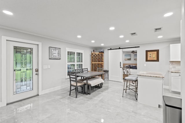 dining room with a barn door and ornamental molding