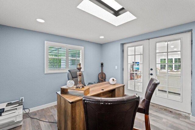 office featuring light hardwood / wood-style floors, a skylight, french doors, and a wealth of natural light