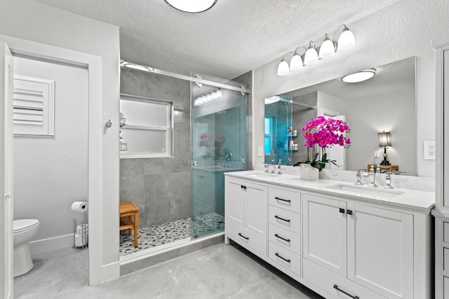 bathroom with vanity, toilet, an enclosed shower, and a textured ceiling