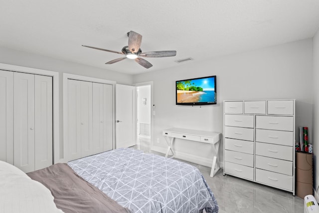 bedroom with ceiling fan and multiple closets