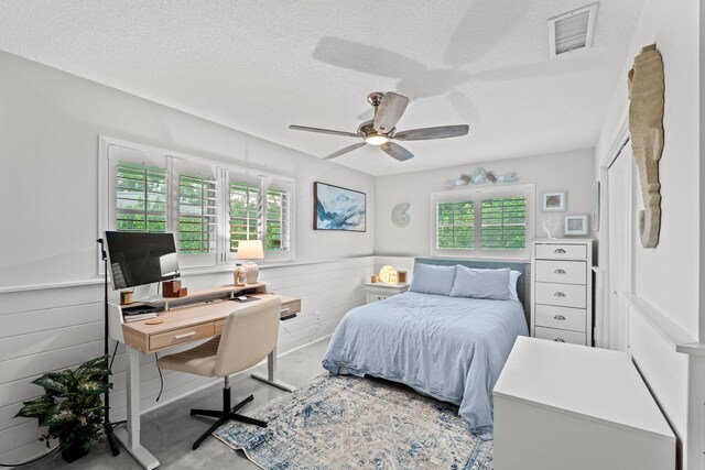 bedroom featuring multiple windows, ceiling fan, and a textured ceiling