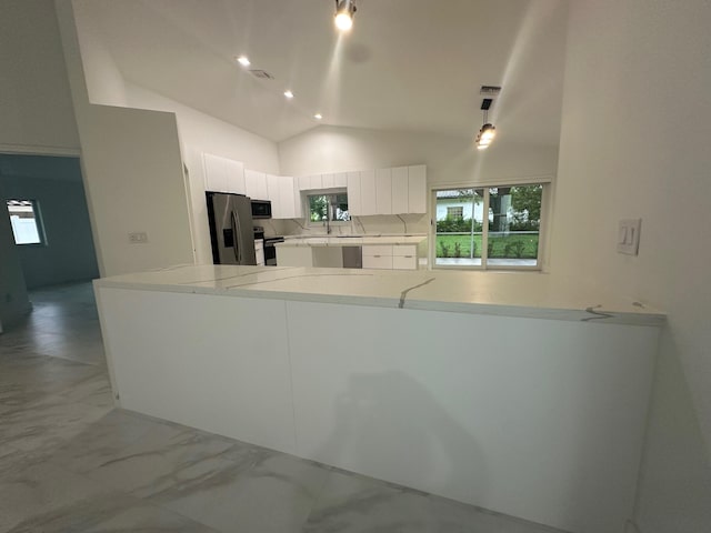 kitchen featuring appliances with stainless steel finishes, lofted ceiling, kitchen peninsula, and white cabinets