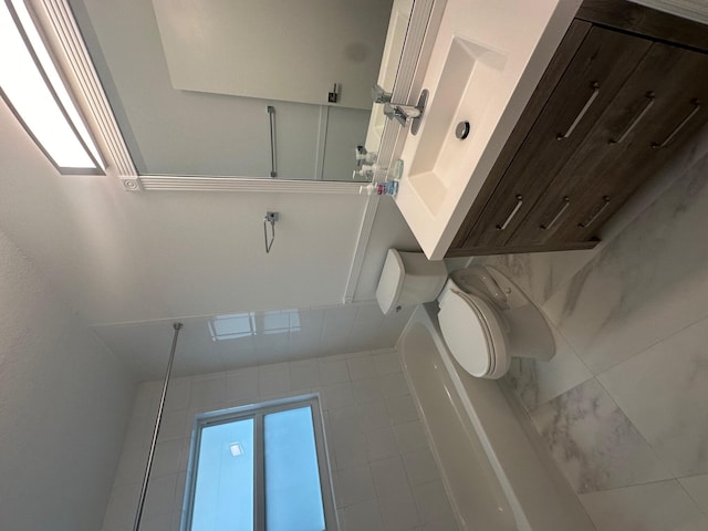 bathroom with tile patterned floors, a healthy amount of sunlight, and toilet