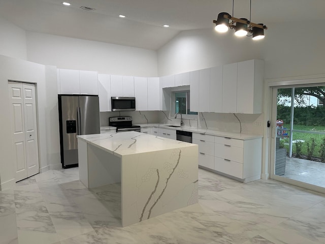 kitchen with high vaulted ceiling, a center island, sink, hanging light fixtures, and appliances with stainless steel finishes