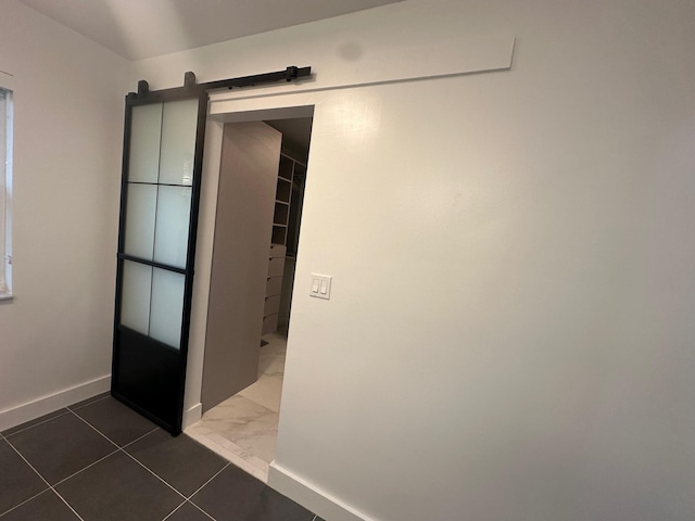 hallway featuring a barn door and dark tile patterned floors