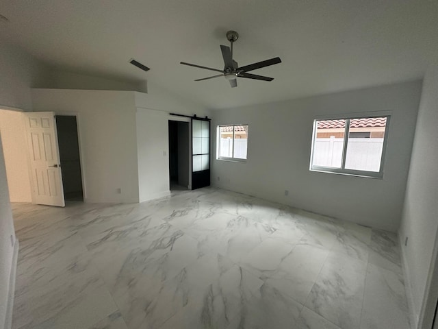 unfurnished bedroom with lofted ceiling, ceiling fan, and a barn door