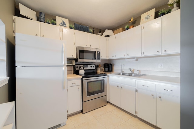 kitchen featuring backsplash, white cabinets, appliances with stainless steel finishes, light tile patterned floors, and sink