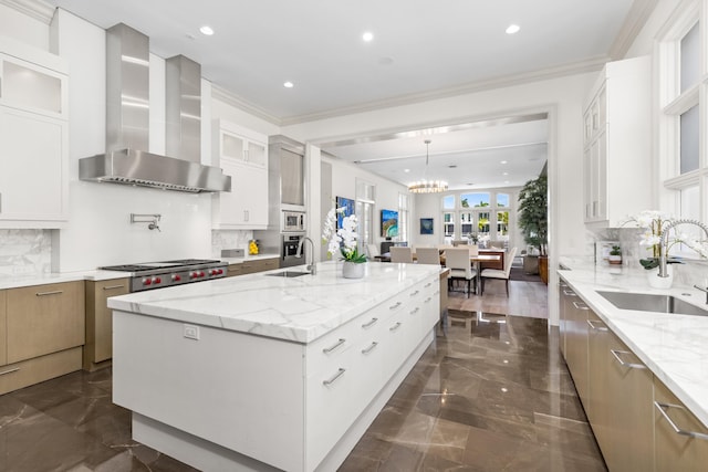 kitchen featuring light stone countertops, sink, wall chimney range hood, a large island with sink, and white cabinets