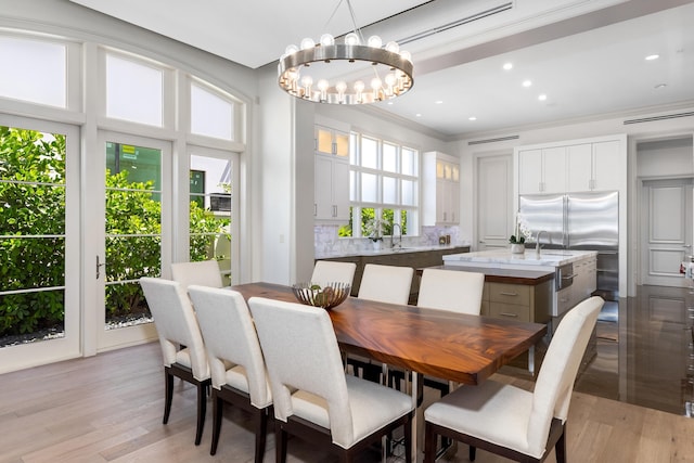 dining space with plenty of natural light, ornamental molding, a notable chandelier, and light wood-type flooring