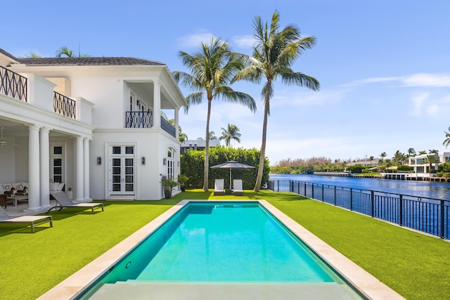 view of swimming pool featuring a lawn and a water view