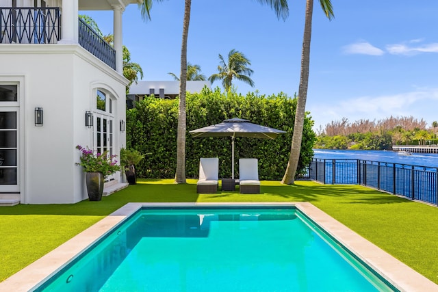 view of pool with a water view and a lawn