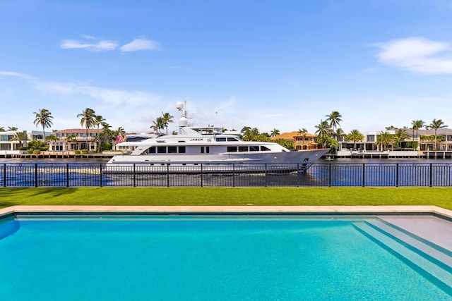 view of swimming pool with a yard and a water view