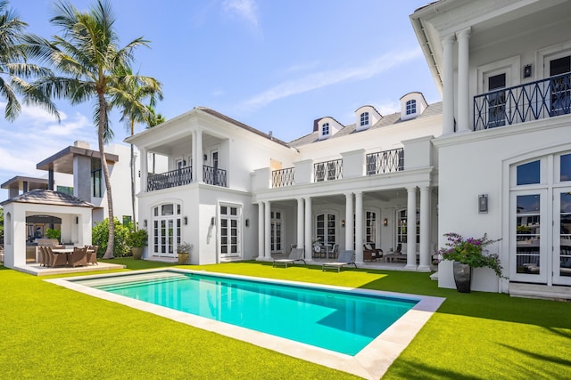 back of property featuring a yard, a balcony, and a patio