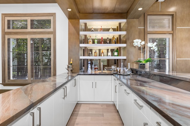 bar featuring wooden ceiling, white cabinetry, dark stone counters, and light hardwood / wood-style flooring