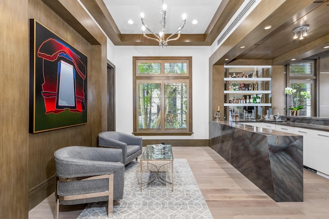 living area featuring light hardwood / wood-style floors, a raised ceiling, and an inviting chandelier