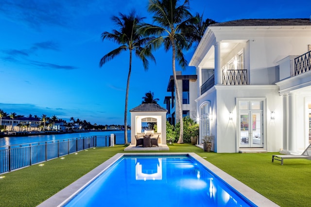 pool at dusk with a lawn and a water view