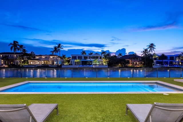 pool at dusk with a lawn and a water view