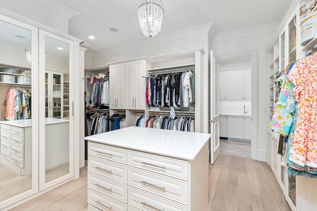 walk in closet with a chandelier and light hardwood / wood-style flooring