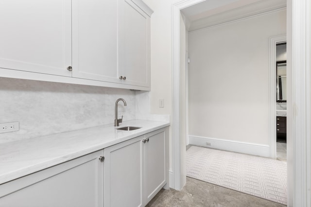 bar with white cabinetry, sink, and crown molding