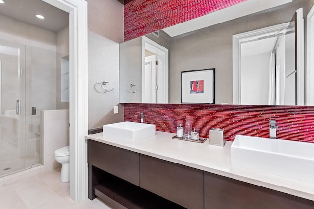 bathroom with an enclosed shower, vanity, toilet, and backsplash