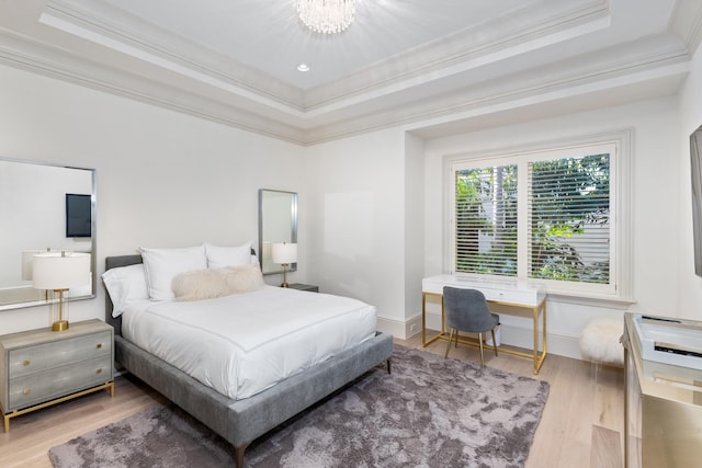 bedroom featuring a raised ceiling, wood-type flooring, crown molding, and a chandelier