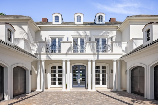 view of exterior entry with a balcony and french doors