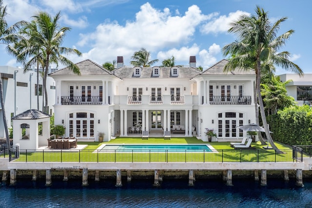 rear view of property featuring a lawn, a water view, a patio, and french doors