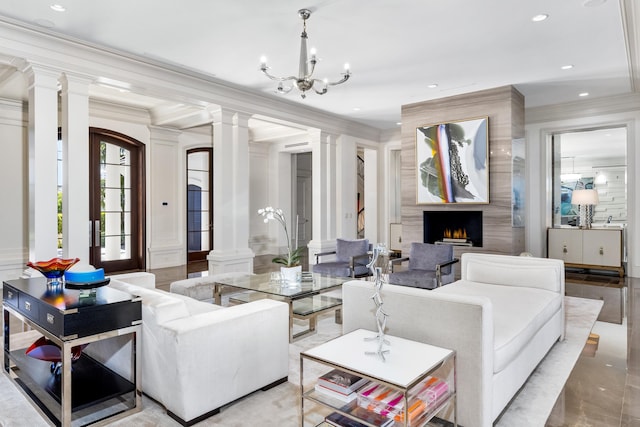 living room with ornate columns, crown molding, a fireplace, and an inviting chandelier