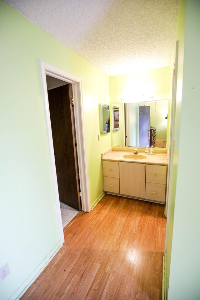 bathroom featuring wood-type flooring, vanity, and a textured ceiling