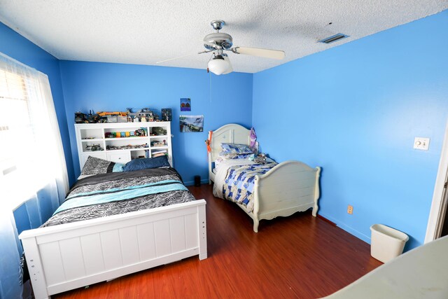 bedroom with ceiling fan, wood-type flooring, and a textured ceiling