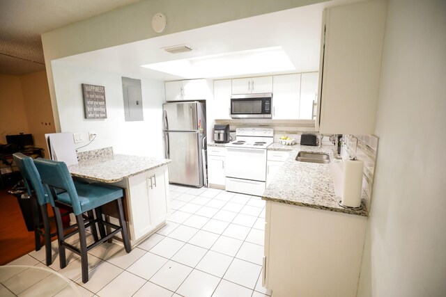 kitchen featuring a breakfast bar area, stainless steel appliances, white cabinetry, light tile patterned floors, and sink