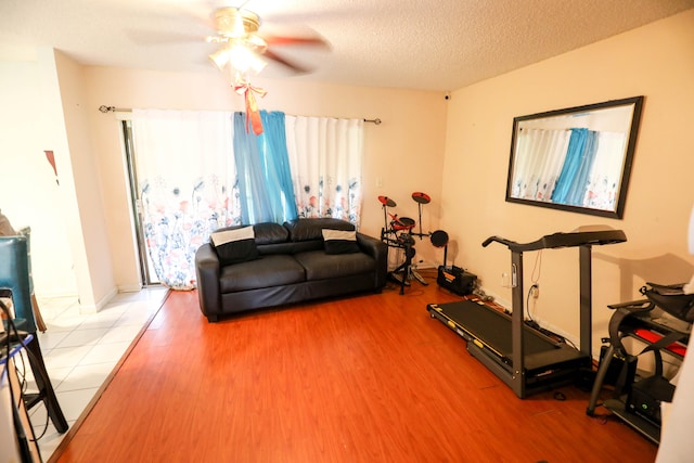 exercise area with hardwood / wood-style floors, a textured ceiling, and ceiling fan