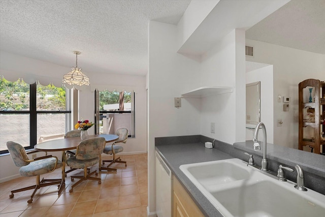 kitchen featuring dishwasher, sink, a textured ceiling, and light tile patterned floors