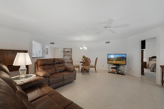 living room featuring ceiling fan with notable chandelier, a textured ceiling, and light tile patterned floors