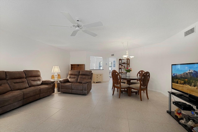 living room featuring light tile patterned flooring, ceiling fan with notable chandelier, and a textured ceiling